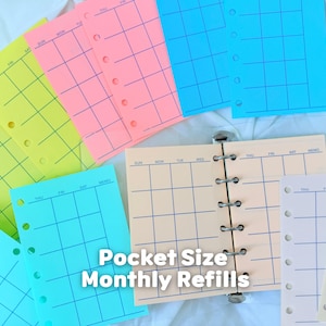 May include: A collection of pocket-size monthly calendar refill pages in various colors including neon yellow, pink, blue, and cream. The pages feature a grid layout with printed days of the week and punched holes for binder rings. Text reads Pocket Size Monthly Refills.