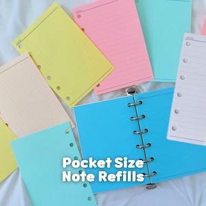 May include: A collection of colorful loose-leaf paper refills for a binder, including yellow, pink, blue, and white sheets. Some pages feature grid patterns, while others are lined. Each sheet has a column of punched holes and the word DATE printed.