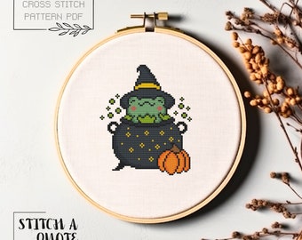 May include: Cross stitch pattern PDF of a green frog wearing a witch's hat and sitting in a black cauldron with a pumpkin next to it. The text "Stitch a Quote" is at the bottom of the image.