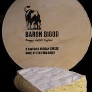 May include: A circular wooden cheese board featuring the text "BARON BIGOD" and a cow illustration. In front is a square of cheese with a white rind and a creamy interior. The board also states "A RAW MILK ARTISAN CHEESE MADE BY FEN FARM DAIRY."
