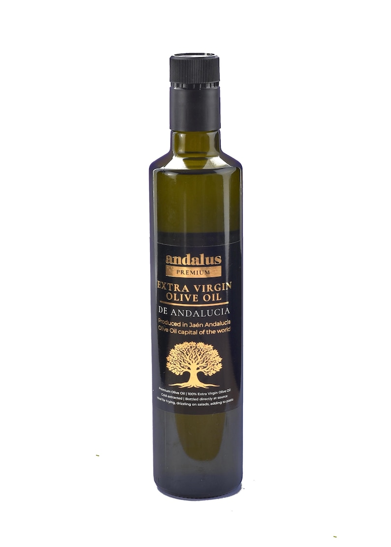 May include: A tall, dark green glass bottle of Andalus Premium Extra Virgin Olive Oil. The black label features gold text, a gold olive tree illustration, and the text: Produced in Ja&eacute;n Andalucia, Olive Oil capital of the world.