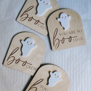May include: Four wooden signs with a ghost cutout and the text "boo" on each. Two signs say "boo crew" and two signs say "you are so boo-tiful".