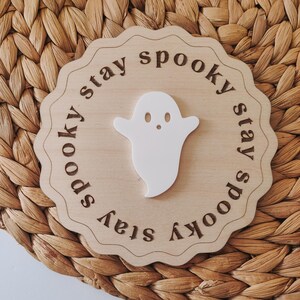 May include: A wooden sign with a white ghost cutout and the text "stay spooky stay spooky" around the edge.