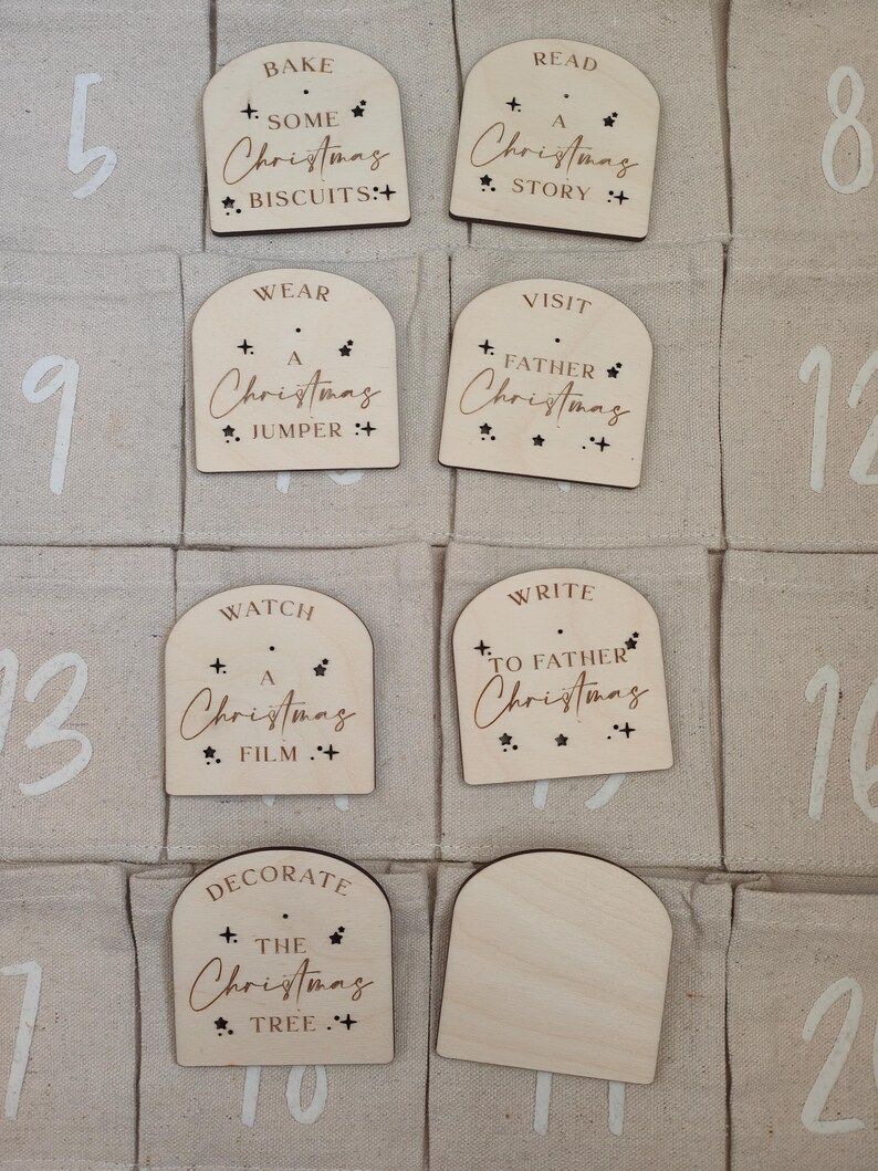 K&ouml;nnte beinhalten: Ein Adventskalender aus Holz mit 12 nummerierten F&auml;chern. Jedes Fach hat eine kleine Holzt&uuml;r mit einer weihnachtlichen Aktivit&auml;t darauf geschrieben. Die Aktivit&auml;ten umfassen "Backen Sie Weihnachtskekse", "Lesen Sie eine Weihnachtsgeschichte", "Tragen Sie einen Weihnachtspullover", "Besuchen Sie den Weihnachtsmann", "Sehen Sie sich einen Weihnachtsfilm an", "Schreiben Sie an den Weihnachtsmann" und "Schm&uuml;cken Sie den Weihnachtsbaum".