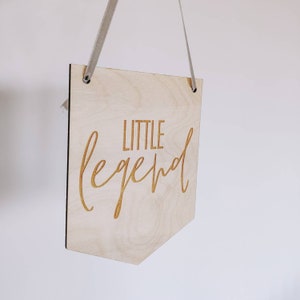 May include: A wooden sign with the text "LITTLE legend" in a cursive font. The sign is hanging from a white string.