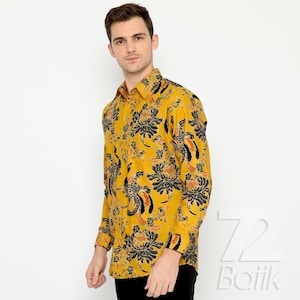 Puede incluir: Una camisa de manga larga con fondo amarillo y un estampado floral negro y naranja.