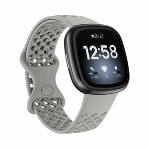 May include: A grey smartwatch with a black screen showing the time, date, and activity metrics. The watch has a grey perforated silicone strap. The screen displays "WED 23" and the time "12:58".