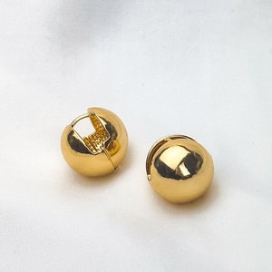 May include: A pair of gold hoop earrings. The earrings are round and have a smooth finish.