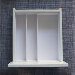 Peut inclure: Étagère murale rectangulaire blanche à trois compartiments. L'étagère a un design minimaliste, avec une base plate et un cadre surélevé. Les compartiments sont divisés par des séparateurs verticaux, créant un espace de rangement.