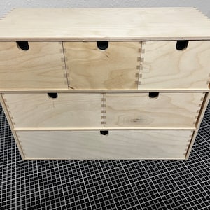 May include: A wooden drawer organizer with six drawers. The drawers are made of light wood and have a simple design.