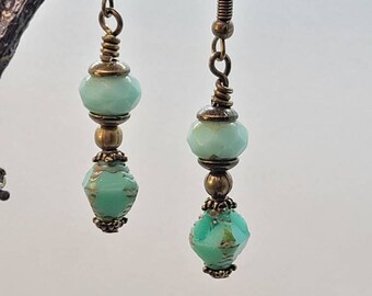 May include: A pair of dangle earrings with turquoise blue faceted glass beads and antique gold tone metal accents.