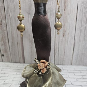 May include: Gold tone dangle earrings with green and gold striped beads and a gold tone round bead.