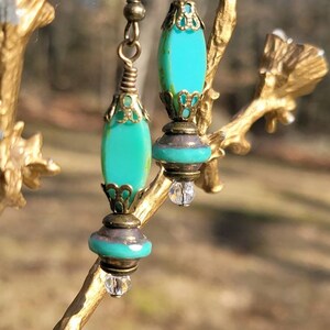 May include: A pair of turquoise blue glass dangle earrings with antique brass accents and crystal beads.