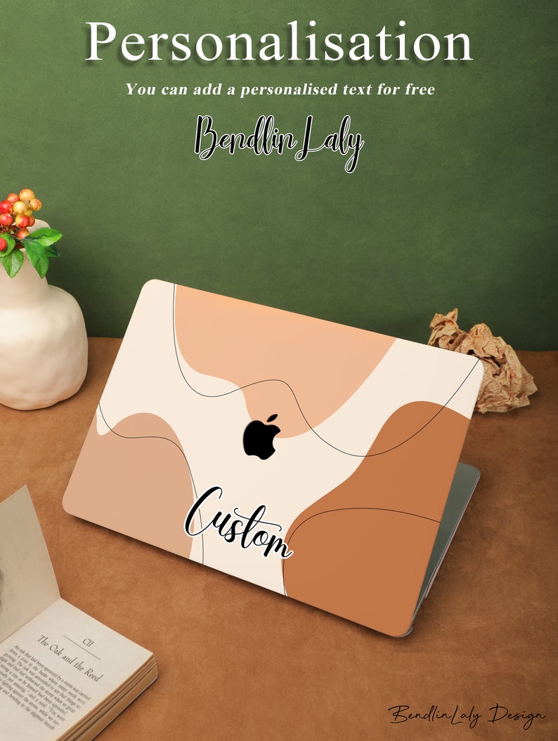 May include: A laptop with a custom design featuring abstract shapes in shades of brown, beige, and white. The design includes the word "Custom" in black cursive lettering. The laptop is on a brown surface with a book and a vase of red berries.