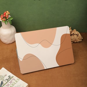 May include: A laptop skin with an abstract design featuring beige, brown, and white colors. The skin has a modern, minimalist aesthetic and is designed to protect the laptop from scratches and wear.