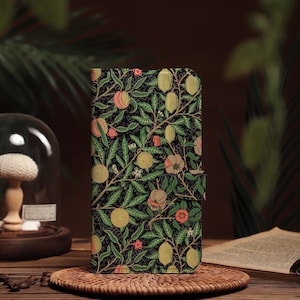 Könnte beinhalten: Eine Handyhülle mit schwarzem Hintergrund und einem botanischen Muster mit grünen Blättern, gelben und rosa Früchten und roten Blüten. Die Hülle ist geschlossen und hat einen Magnetverschluss.