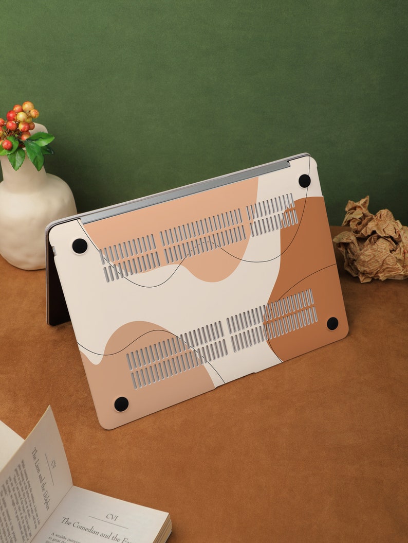 May include: A white laptop case with a brown and beige abstract design. The case has a textured surface and a black rubberized bottom.