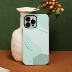 Könnte beinhalten: Eine hellblaue Handyhülle mit einem weißen abstrakten Design. Die Hülle hat einen Kameraausschnitt und ist für ein Handy mit einer Dreifachkamera geeignet.