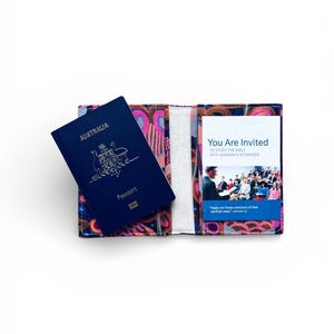 May include: An open passport holder with a colorful pattern, holding an Australian passport. The holder has a design with pink, purple, and orange shapes. A card inside reads "You Are Invited" to study the Bible with Jehovah's Witnesses.
