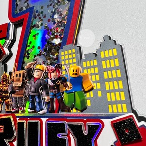 May include: A red, white, and blue glitter-filled number seven cake topper with a cityscape backdrop. The cityscape is made of gray cardboard with yellow windows. Four Roblox characters stand in front of the cityscape. The characters are wearing different outfits and holding various accessories. The cake topper says "Riley" in black letters.