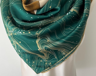 May include: A square silk scarf featuring a deep emerald green base with a pattern of thin, flowing gold lines and white paint-like splatters. The scarf includes sections of tan and brown striped fabric along the edges, creating a layered look.