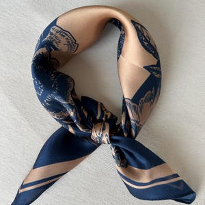 May include: A navy blue and brown silk scarf with a floral print. The scarf is tied in a knot and the ends are hanging down.