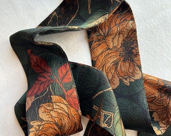 May include: A green and brown ribbon with a floral print. The flowers are orange and red with a detailed design.