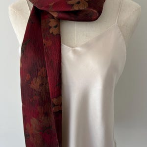 May include: A set of three ceramic mugs with a speckled, cream-colored glaze. Each mug features a different hand-painted floral design in shades of blue, green, and yellow. The mugs have a simple, rounded shape and a comfortable handle.