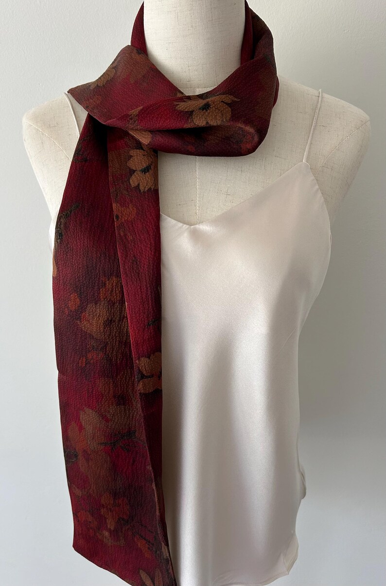 May include: A set of three ceramic mugs with a speckled, cream-colored glaze. Each mug features a different hand-painted floral design in shades of blue, green, and yellow. The mugs have a simple, rounded shape and a comfortable handle.