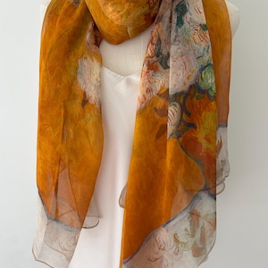 May include: A lightweight scarf featuring a vibrant mustard yellow base color with an intricate floral print in shades of white, green, and soft orange. The fabric has a semi-sheer, delicate texture with a finished hem along the edges.