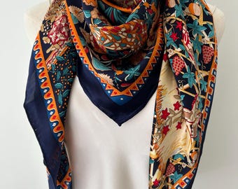 May include: A square scarf featuring a dark navy blue background with a vibrant botanical print of flowers, strawberries, and foliage in shades of red, orange, teal, and cream. The scarf has a decorative border with geometric patterns in orange and blue.