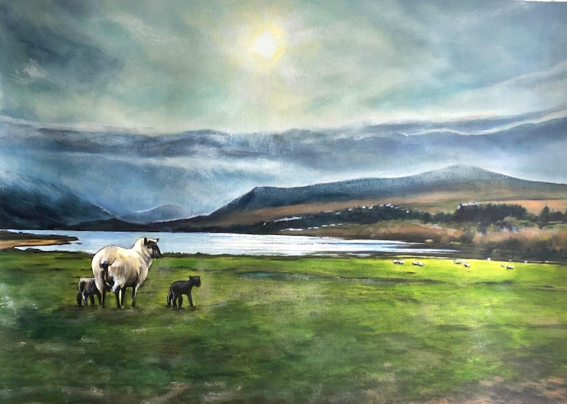 Op de afbeelding: Een schilderij van een schaap en twee lammeren in een weiland, met een meer en bergen op de achtergrond. De lucht is bewolkt en de zon schijnt door de wolken.