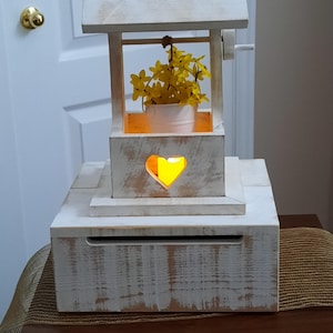Boîte en carton « Puits à souhaits » en cèdre blanc vieilli avec cœur découpé, seau blanc et bougie vacillante sans flamme. (Fleurs non incluses)