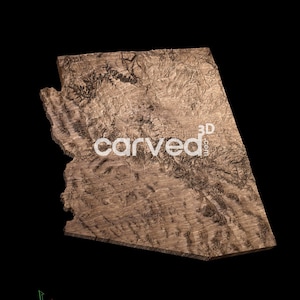 May include: A 3D wood carving of the state of Arizona. The carving is made of a light brown wood and shows the state's natural features in detail. The carving is signed "3D carved.com" in the lower right corner.