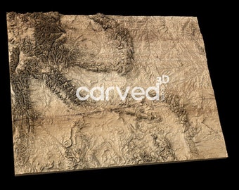 May include: A 3D relief map of a mountainous region, carved from wood. The map is a light brown color with darker brown lines representing the mountains and valleys. The map is tilted slightly to the right, giving it a three-dimensional appearance. The word "carved" is visible in the lower center of the map.