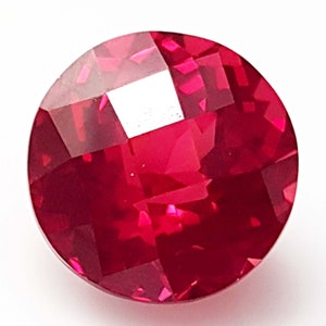 May include: A round, red gemstone with a faceted cut. The gemstone is set in a clear, round setting.