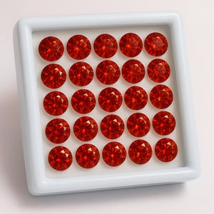 Peut inclure: Un plateau blanc avec 36 pierres précieuses rondes de couleur rouge disposées en grille.