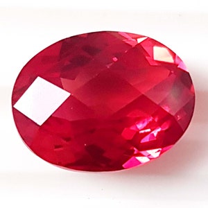 May include: A deep red oval-shaped gemstone with a faceted cut.