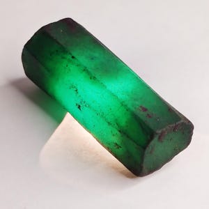 Op de afbeelding: Een groot, donkergroen smaragd kristal met een zeshoekige vorm. Het kristal is ruw en heeft een natuurlijke, onbewerkte afwerking.
