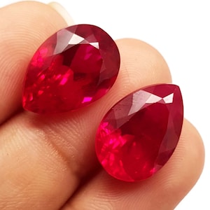 May include: Two pear-shaped red gemstones with a faceted cut.