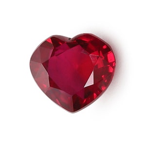 May include: A deep red heart-shaped gemstone with a faceted cut.