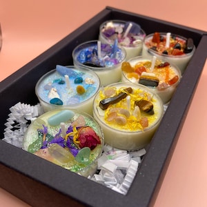 Könnte beinhalten: Ein Set mit sechs Teelichtern in einer schwarzen Box. Jede Kerze ist mit verschiedenen farbigen Kristallen und Glitzer gefüllt. Die Kerzen sind in einer Reihe angeordnet, wobei die Kristalle sichtbar sind.