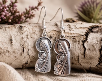 May include: Silver-toned dangle earrings featuring a religious motif. Each earring depicts a woman in a head covering holding a child. The earrings have a detailed, antique appearance and are suspended from simple fish hook ear wires.