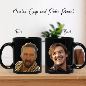 May include: Black ceramic coffee mug with a photo of Nicolas Cage on the front and Pedro Pascal on the back. The mug has a white handle.