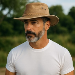 May include: A tan-colored, wide-brimmed hat with a braided band and three small eyelets. The hat is made of a soft material and has a slightly distressed appearance. The hat's brim measures approximately 3 inches.