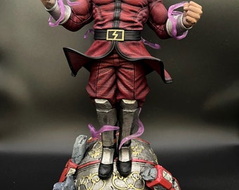 Puede incluir: Una figura de acción roja y negra de un personaje con una base roja y dorada. El personaje está en una pose de lucha con un uniforme rojo y negro y un sombrero rojo con un emblema dorado. La figura está rodeada de energía púrpura.