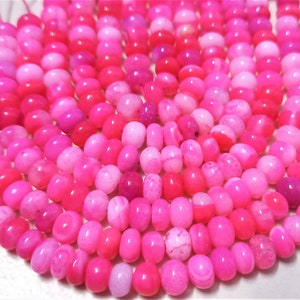 Pode incluir: Um fio de contas de ágata rosa e branca. As contas são de forma oval e têm um acabamento liso e polido.