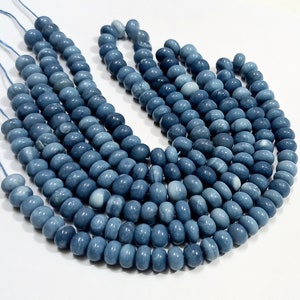 May include: A strand of blue gemstone beads, with a smooth, rounded shape. The beads are strung on a thin, white cord.