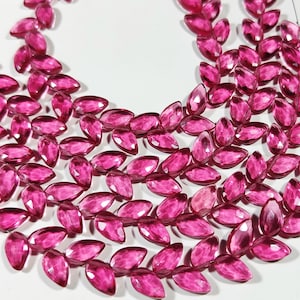 Pode incluir: Um fio de contas de pedras preciosas facetadas cor de rosa em forma de marquise. As contas são enfiadas em um fio fino e estão dispostas em um padrão solto e fluido.