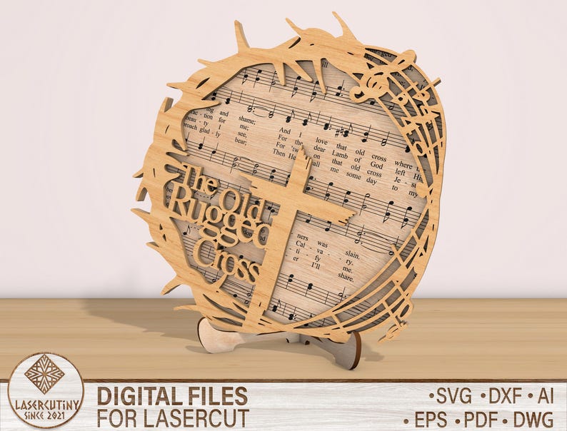 May include: A laser cut wooden design of a cross with a crown of thorns and the words "The Old Rugged Cross" on it. The design is based on a hymn sheet with musical notes.